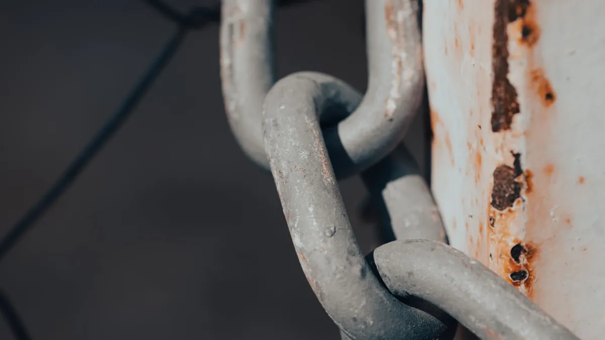 Close-up shot of a rusty metal chain wrapped around a weathered post.